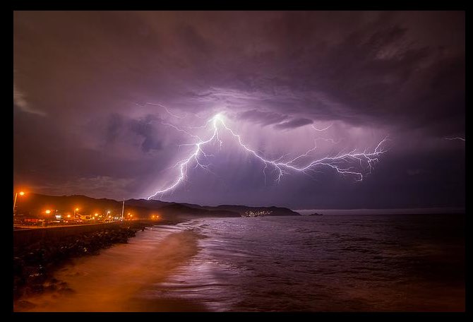 A lightning strike is seen over the ocean.