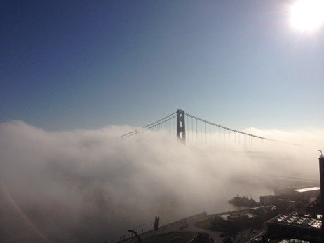 A bridge is in the middle of a cloud filled sky.