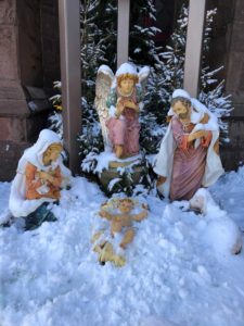 A group of statues in the snow with trees.